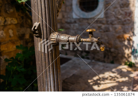 Close-up of ornate bronze water tap. Vintage craftsmanship, historical design, and functional detail. Close-up of ornate bronze water tap. Vintage craftsmanship, historical design, and functional detail. 135061874