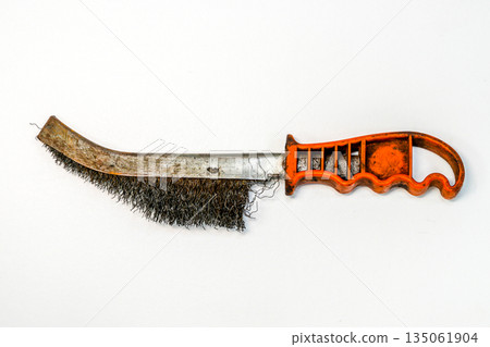 Worn wire brush with orange handle isolated on white background, used metal cleaning hand tool Worn wire brush with orange handle isolated on white background, used metal cleaning hand tool 135061904