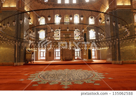 Beautiful interior of Yeni Cami Mosque with large circular chandeliers, red carpet and stained glass windows in Eminonu, Istanbul 135062588