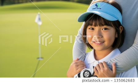 一位微笑的青少年高爾夫球手女孩在球場上被一位成年人擁抱。 135062683