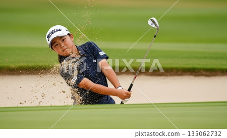 A junior golfer girl makes a brilliant escape from a difficult golf bunker 135062732