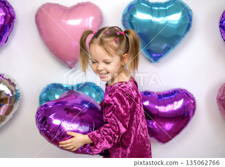 Funny girl playing with a heart-shaped balloon on Valentine's day Funny girl playing with a heart-shaped balloon on Valentine's day 135062766
