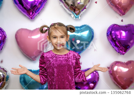 A girl on a background with multicolored helium foil balloons sprinkles pink confetti. Valentine's Day Invitation Party A girl on a background with multicolored helium foil balloons sprinkles pink confetti. Valentine's Day Invitation Party 135062768