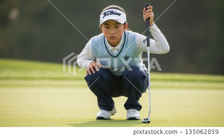 一位小學女學生高爾夫球手在推桿前專心致志地觀察球場。 135062859