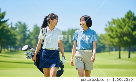 A junior golfer girl walking and chatting on a sunny golf course 135062880