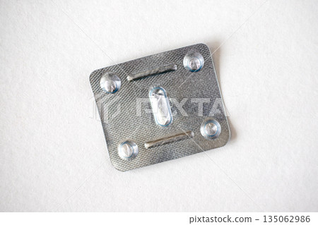 Empty metal used blister pack for one tablet, isolated on white background. Metal capsule blister top view. Empty metal used blister pack for one tablet, isolated on white background. Metal capsule blister top view. 135062986