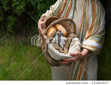 Man holding a basket with fish and bread Man holding a basket with fish and bread 135063037