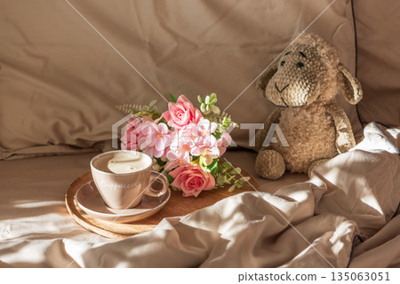 Cappuccino with Flowers and Plush Sheep on Cozy Bed under Morning Sunlight Cappuccino with Flowers and Plush Sheep on Cozy Bed under Morning Sunlight 135063051