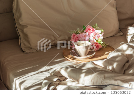 Cappuccino Cup and Flowers on Tray with Satin Bedding in Sunlight. Valentine's or Mother's Day Celebration 135063052