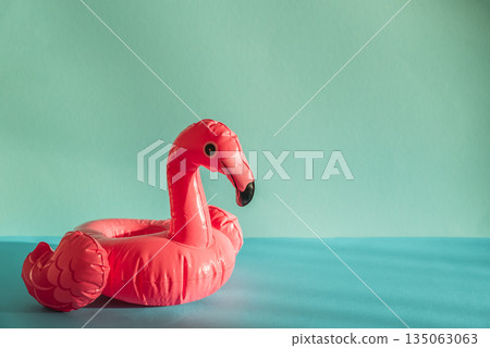 Pink Flamingo Shaped Pool Float on Turquoise Water under Sunlight. Front view 135063063