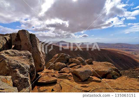 View on the dry soil of Fuerteventura with a passing road 135063151