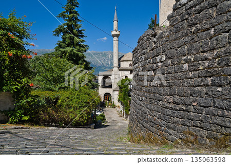 A sturdy brick wall with a mosque located in the background in Gjirokastra 135063598