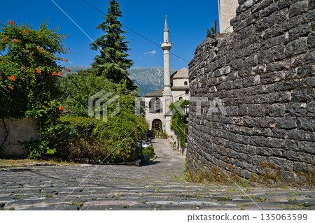 A sturdy brick wall with a mosque located in the background in Gjirokastra 135063599