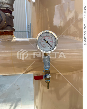 Pressure gauge attached to a storage tank in an industrial facility during daylight hours 135063979
