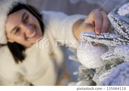 Woman Decorating Snowy Christmas Tree with Ornament Woman Decorating Snowy Christmas Tree with Ornament 135064118