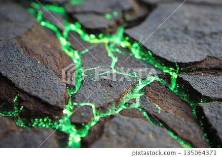 Volcanic rock surface displaying green luminescent features in a textured landscape 135064371