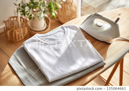 Freshly washed white t-shirt and ironing board in bright interior during day time 135064661