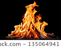 Flames dance around logs in a bright campfire at night under a starry sky 135064941