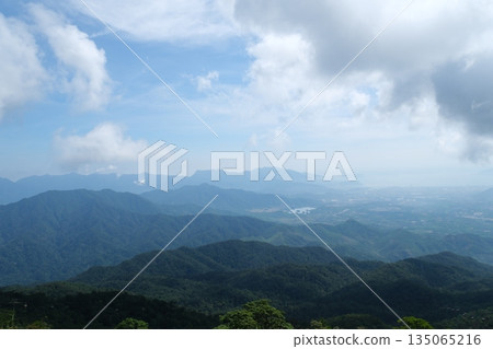 A breathtaking view of a majestic mountain range, with a few scattered clouds in the sky 135065216