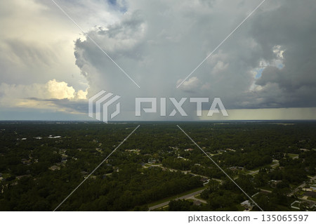 Landscape of dark ominous clouds forming on stormy sky during heavy thunderstorm over rural town area 135065597