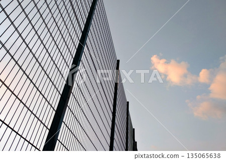 High wire mesh fence in restricted area on blue sky background. 135065638