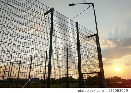 High wire mesh fence in restricted area on blue sky background. 135065639