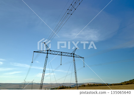 High voltage tower with electric power lines transfening electrical energy through cable wires 135065640