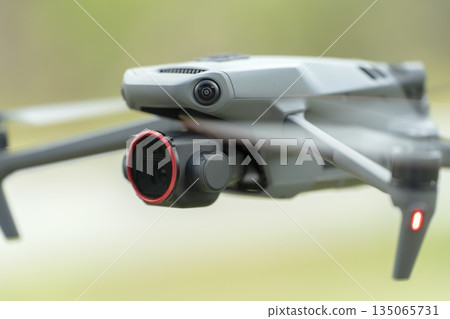 Drone aircraft with blurred fast rotating propellers and video camera flying in air Drone aircraft with blurred fast rotating propellers and video camera flying in air 135065731