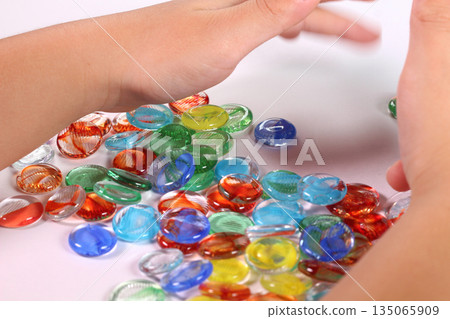 Children's hands playing with marbles Children's hands playing with marbles 135065909
