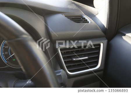 A close-up of the air conditioning vent in the driver's seat of a car. A close-up of the air conditioning vent in the driver's seat of a car. 135066893