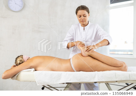 During massage, doctor works out legs shins kneads and stretches and increases mobility in joints During massage, doctor works out legs shins kneads and stretches and increases mobility in joints 135066949