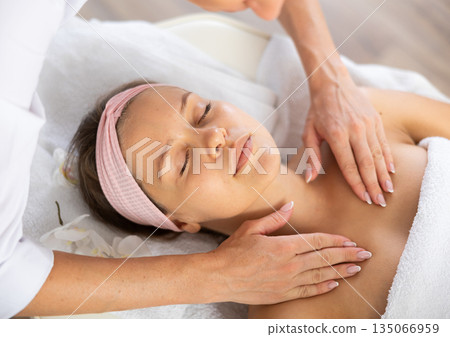 Young woman relaxing in spa salon during clavicles and neck massage 135066959
