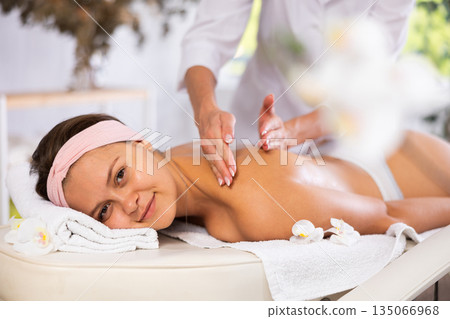 Young woman relaxing in spa center during back and shoulders massage Young woman relaxing in spa center during back and shoulders massage 135066968