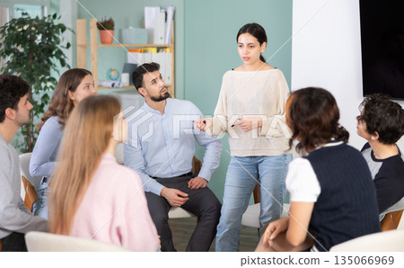 Young girl standing and talking to students sitting in a circle Young girl standing and talking to students sitting in a circle 135066969