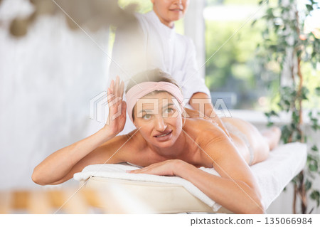 Young woman suffering from discomfort during deep tissue massage session Young woman suffering from discomfort during deep tissue massage session 135066984