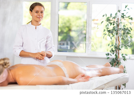 Female physiotherapist poses against background of spa salons office. 135067013