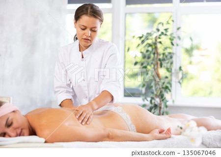 Female masseur works out shoulder and back problem area for female athlete client. Female masseur works out shoulder and back problem area for female athlete client. 135067046