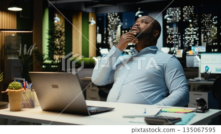 African american analyst focusing on a complex problem in a dark office at night, strategizing and envisioning options with laptop open. Seeking a logical solution through deduction. African american analyst focusing on a complex problem in a dark office at night, strategizing and envisioning options with laptop open. Seeking a logical solution through deduction. 135067595