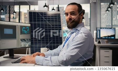 Portrait of happy sustainable energy researcher using simulation software to upgrade solar panels and wind turbines farm. Jolly engineer improving clean energy industry efficiency, camera A Portrait of happy sustainable energy researcher using simulation software to upgrade solar panels and wind turbines farm. Jolly engineer improving clean energy industry efficiency, camera A 135067615