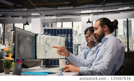 Research and development office coworkers use CAD program to upgrade production lines for sustainable solar panel assembly. Team of engineers runs simulation to make solar cells eco friendly, camera A 135067616