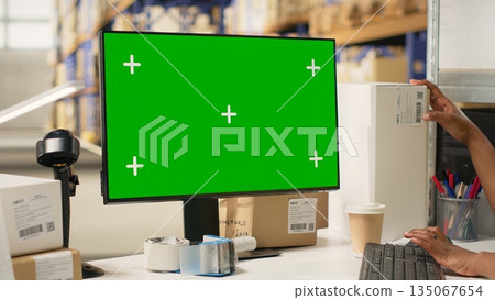 Woman warehouse clerk handling shipment protocols with copy space on pc, working on large business operations for retail industry. Depot filled with cardboard boxes on racks. Camera B. Woman warehouse clerk handling shipment protocols with copy space on pc, working on large business operations for retail industry. Depot filled with cardboard boxes on racks. Camera B. 135067654