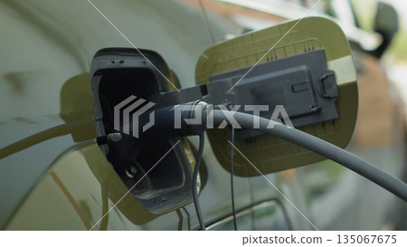 Closeup of zero emission EV vehicle connected to charging dock, emphasizing commitment to cleaner environment. Electric car plugged into power supply, part of global push for decarbonizing transport 135067675