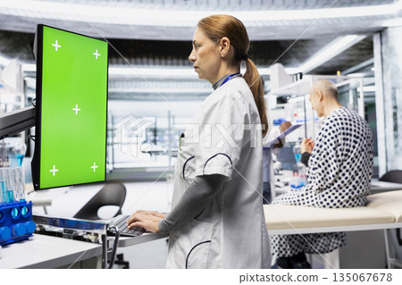 Chroma key in vertical position next to nurse observing new drug testing, monitoring vitals and documenting dosage reactions in modern laboratory. Pharmacology research for progress. 135067678