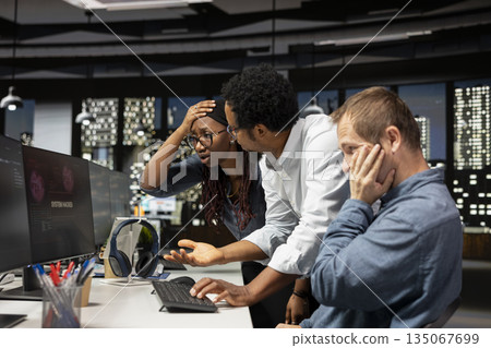 Stressed tech startup workers troubled by hacker spyware virus stealing sensitive information. Anxious IT specialists in office worried by servers network attack from scammers 135067699