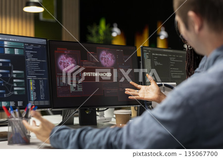 Close up of system administrators in office trying to fix hacking attempt on corporate network. Tech startup coworkers investigating unauthorized access alerts, brainstorming ways to mitigate damages Close up of system administrators in office trying to fix hacking attempt on corporate network. Tech startup coworkers investigating unauthorized access alerts, brainstorming ways to mitigate damages 135067700