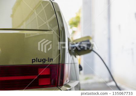 Close up of plug in electric vehicle charging, connected to electric cable. Power connector plugged into EV car, concept of shift toward sustainable mobility and renewable energy transportation 135067733