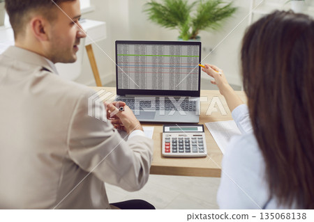 Business Colleagues, Working Together In Office, Doing Accounting On Laptop Business Colleagues, Working Together In Office, Doing Accounting On Laptop 135068138