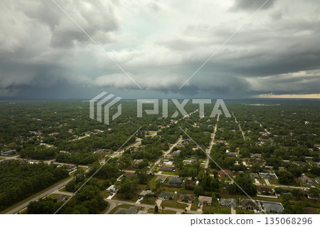 Dark stormy clouds forming on gloomy sky before heavy rainfall over suburban town area 135068296