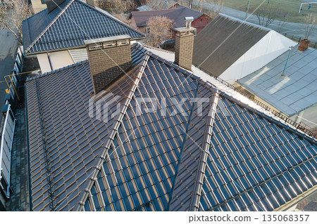 Closeup of house roof top covered with ceramic shingles. Tiled covering of building 135068357