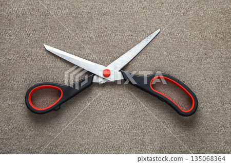 Close-up of sharp steel metal scissors isolated on light cloth copy space background. Household equipment, office or school tools. 135068364